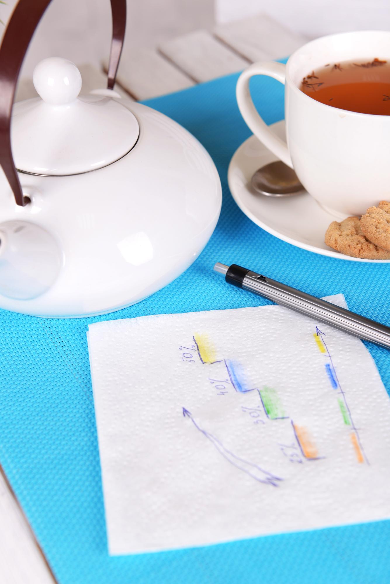 notebook with menu sketches and cups of coffee on table
